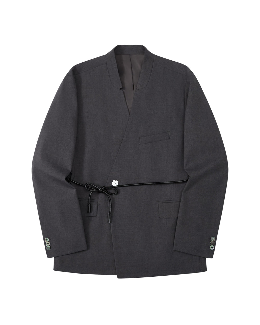 The COLLARLESS TIE BLAZER by Sundae School is a dark gray blazer with an unstructured drape and a shawl collar, designed without buttons. It features a single chest pocket, two front flap pockets, and comes with a thin vegan leather belt that ties at the waist.