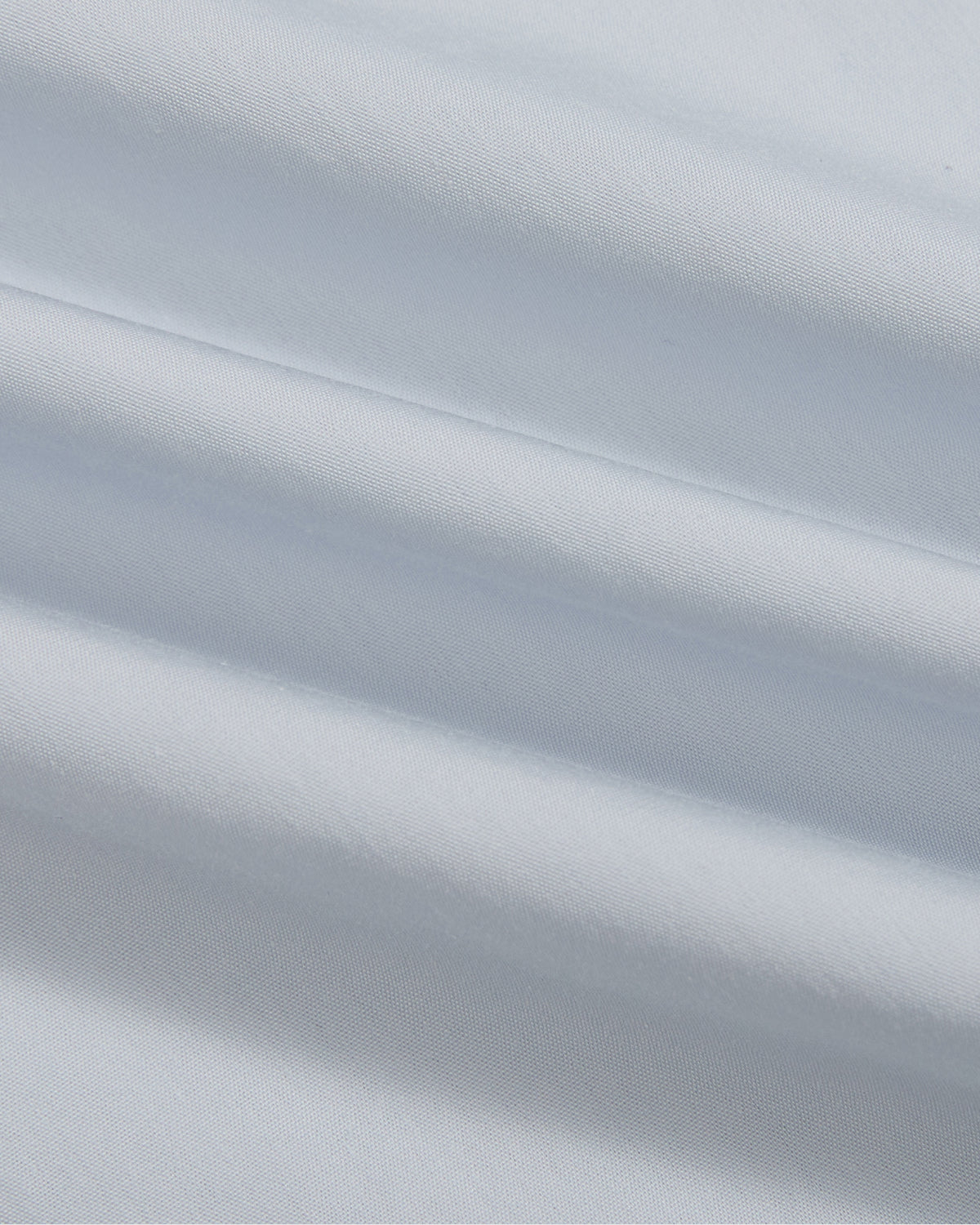 A close-up view of the Sundae School DART COLLAR SHIRT showcases its smooth, white fabric with soft, diagonal folds that create gentle shadows and highlights.