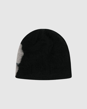The Black Ddul Beanie by Sundae School is a black acrylic hat with a light gray patch on the left side, shown against a plain light gray background.