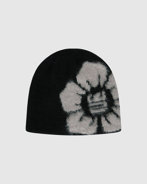 The Black Ddul Beanie by Sundae School is a black acrylic hat featuring a bold, light gray flower on one side, set against a plain light gray background. This stylish beanie blends fashion and comfort in protective headwear.