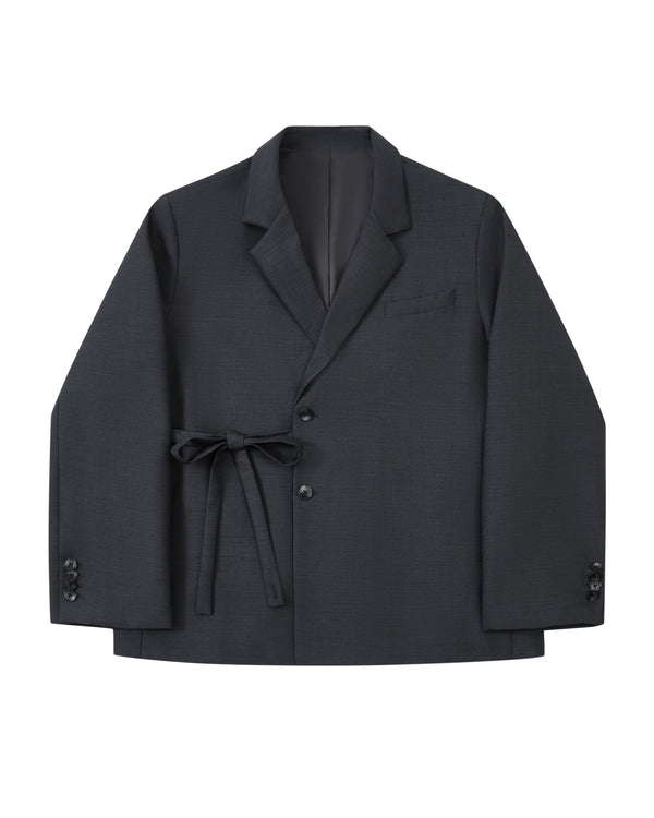 Introducing the CHARCOAL DOUBLE DUTY BLAZER by Sundae School—a refined wool blend blazer in deep charcoal, featuring notched lapels, front button closure, a chest pocket, and a fabric belt elegantly tied at the waist. Inspired by the silhouette of a hanbok, this design is finished with subtle button accents near the cuffs for an elevated touch.