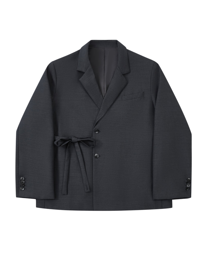 Introducing the CHARCOAL DOUBLE DUTY BLAZER by Sundae School—a refined wool blend blazer in deep charcoal, featuring notched lapels, front button closure, a chest pocket, and a fabric belt elegantly tied at the waist. Inspired by the silhouette of a hanbok, this design is finished with subtle button accents near the cuffs for an elevated touch.