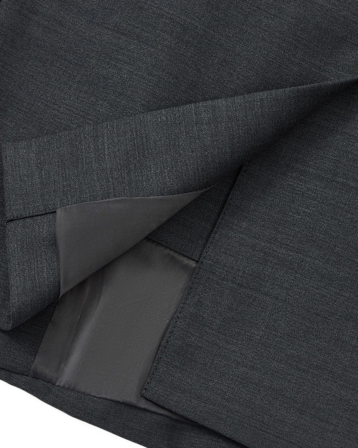 Close-up of the hem and inner lining of the CHARCOAL DOUBLE DUTY BLAZER by Sundae School, highlighting the neat stitching and smooth texture of its premium dark gray wool blend fabric.