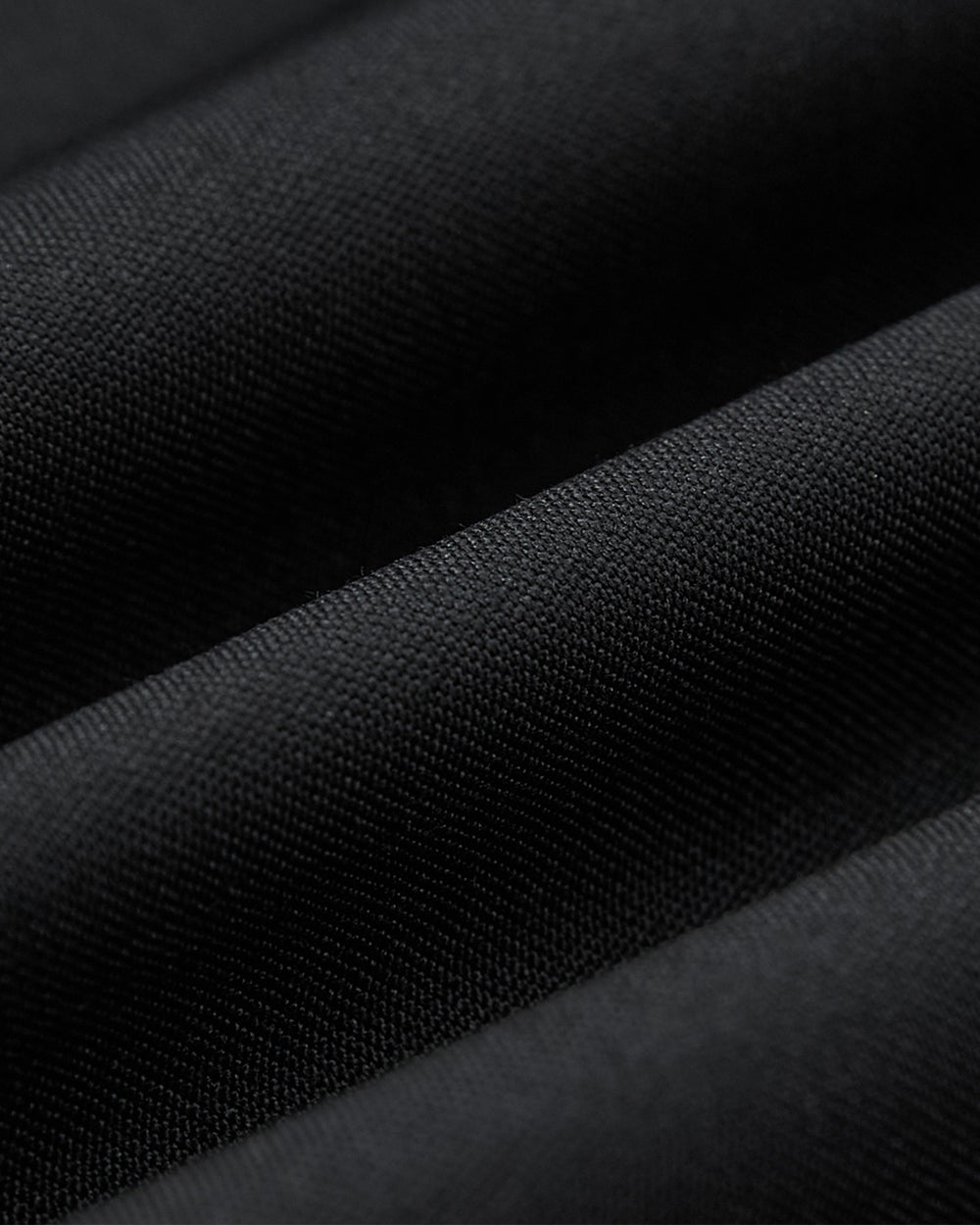 Close-up of textured black fabric with soft, diagonal folds and smooth finish—ideal for the BLACK DOUBLE DUTY BLAZER by Sundae School, perfect for modern hanbok or unisex blazer styles.