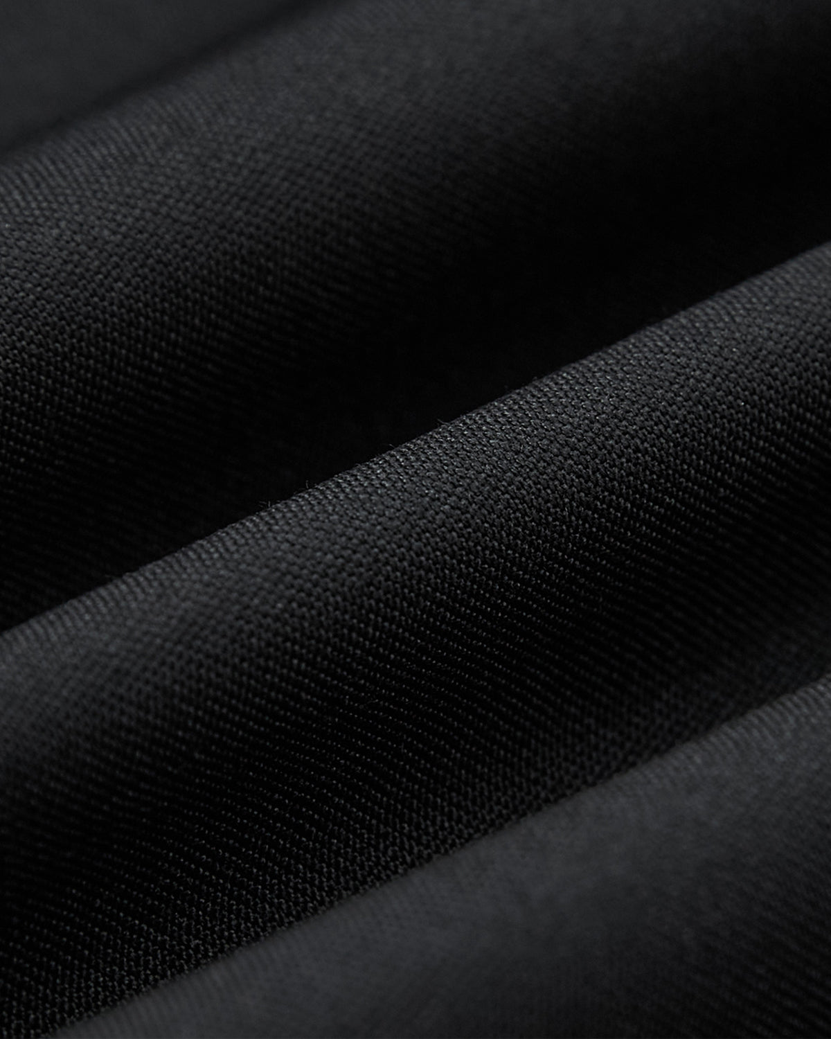 Close-up of textured black fabric with soft, diagonal folds and smooth finish—ideal for the BLACK DOUBLE DUTY BLAZER by Sundae School, perfect for modern hanbok or unisex blazer styles.