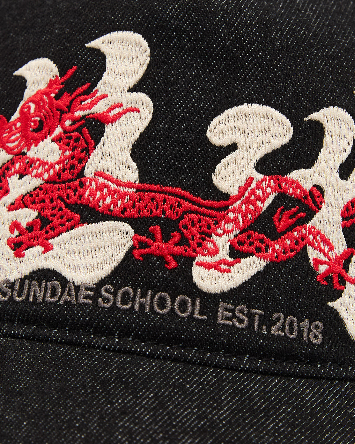 The BLACK DRAGON CAP by Sundae School features black fabric, a red embroidered dragon, white smoke detailing, and 