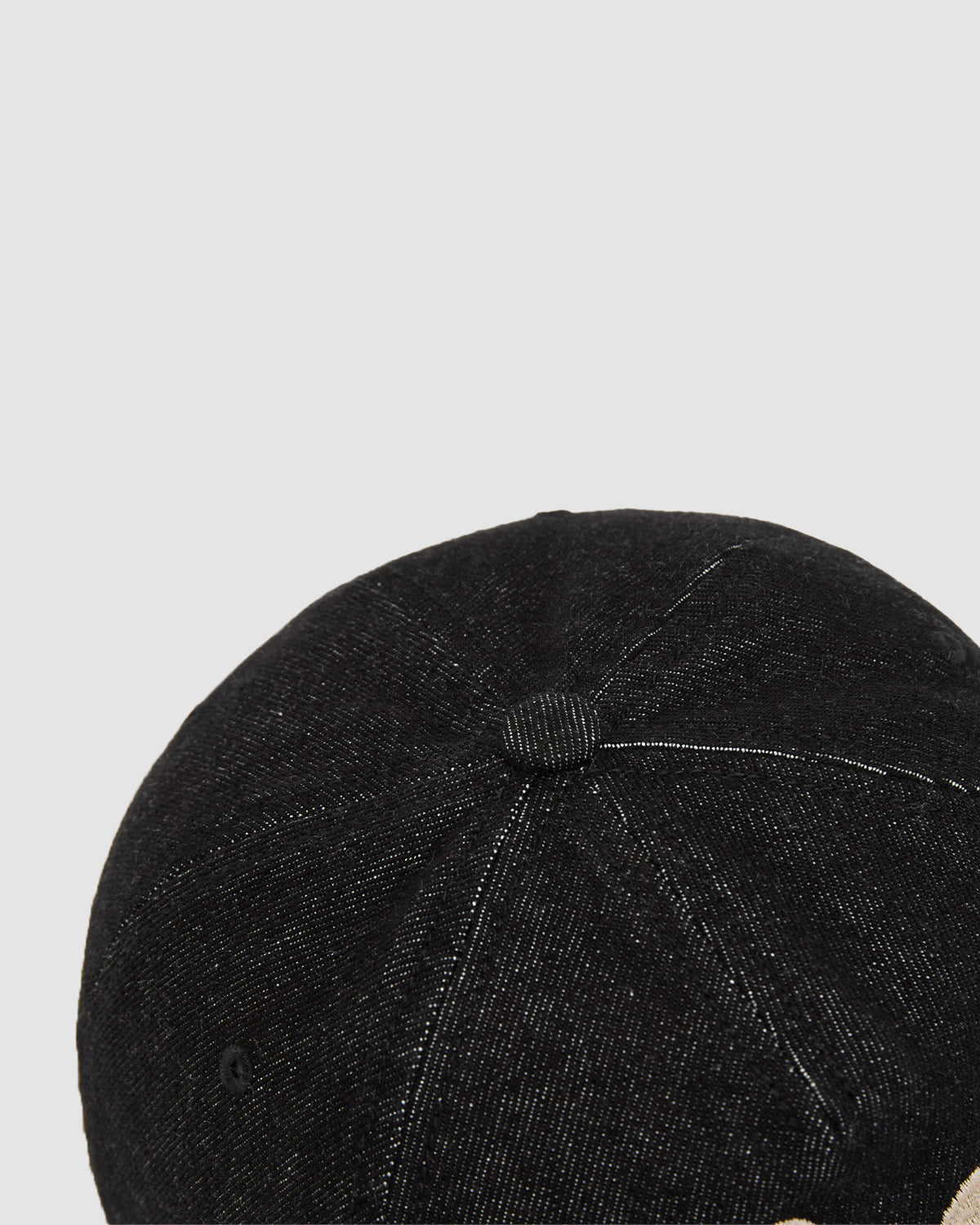 The image features the top section of Sundae School's BLACK DRAGON CAP, a black denim cap with white stitching and a fabric-covered center button, set against a plain light gray background.