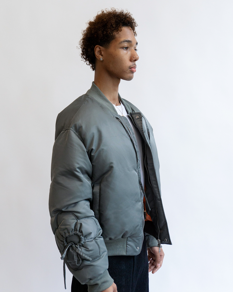 A close up of the upper body of a model wearing Sundae School Khaki Flower Channeled Bomber