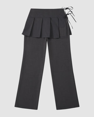 The Sundae School FLARE SKIRT PANTS are black tailored summer wool trousers with a wide waistband, removable pleated skirt overlay, and right side tie detail, shown on a light gray background.
