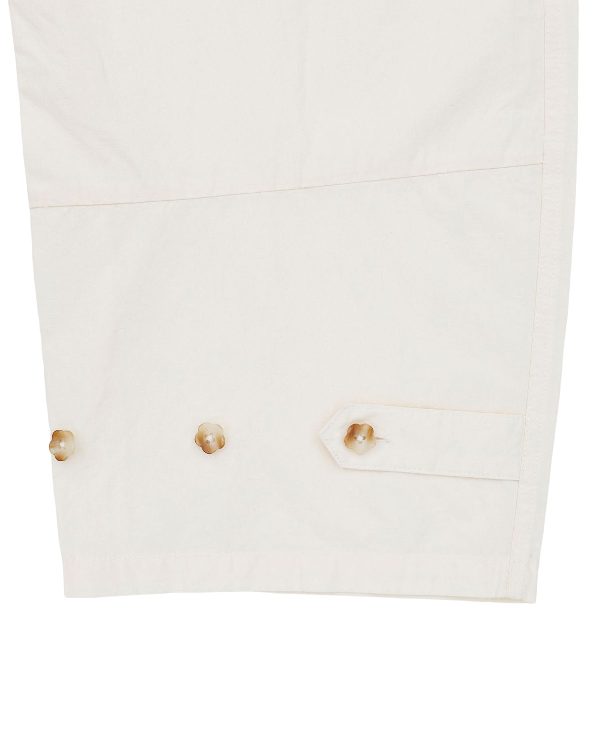 Close-up of the cuff on the IVORY FLOWER NORIGAE LINEN TROUSERS by Sundae School, featuring three brown buttons and a decorative tab on white cotton linen, highlighting detailed stitching on the fabric.