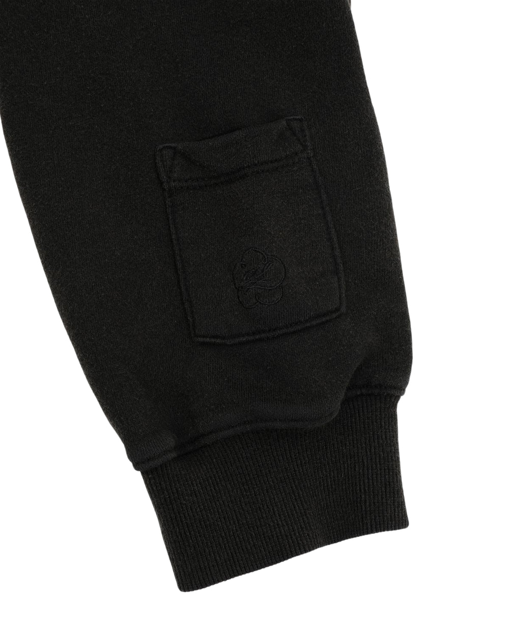 Close-up of the BLACK WASH FLOWER KNOT ZIP UP by Sundae School, showcasing the black cotton sleeve with a small pocket and subtle Hangul Sundae School embroidery above the ribbed cuff, finished with an intricate Maehwa knot zipper pull.