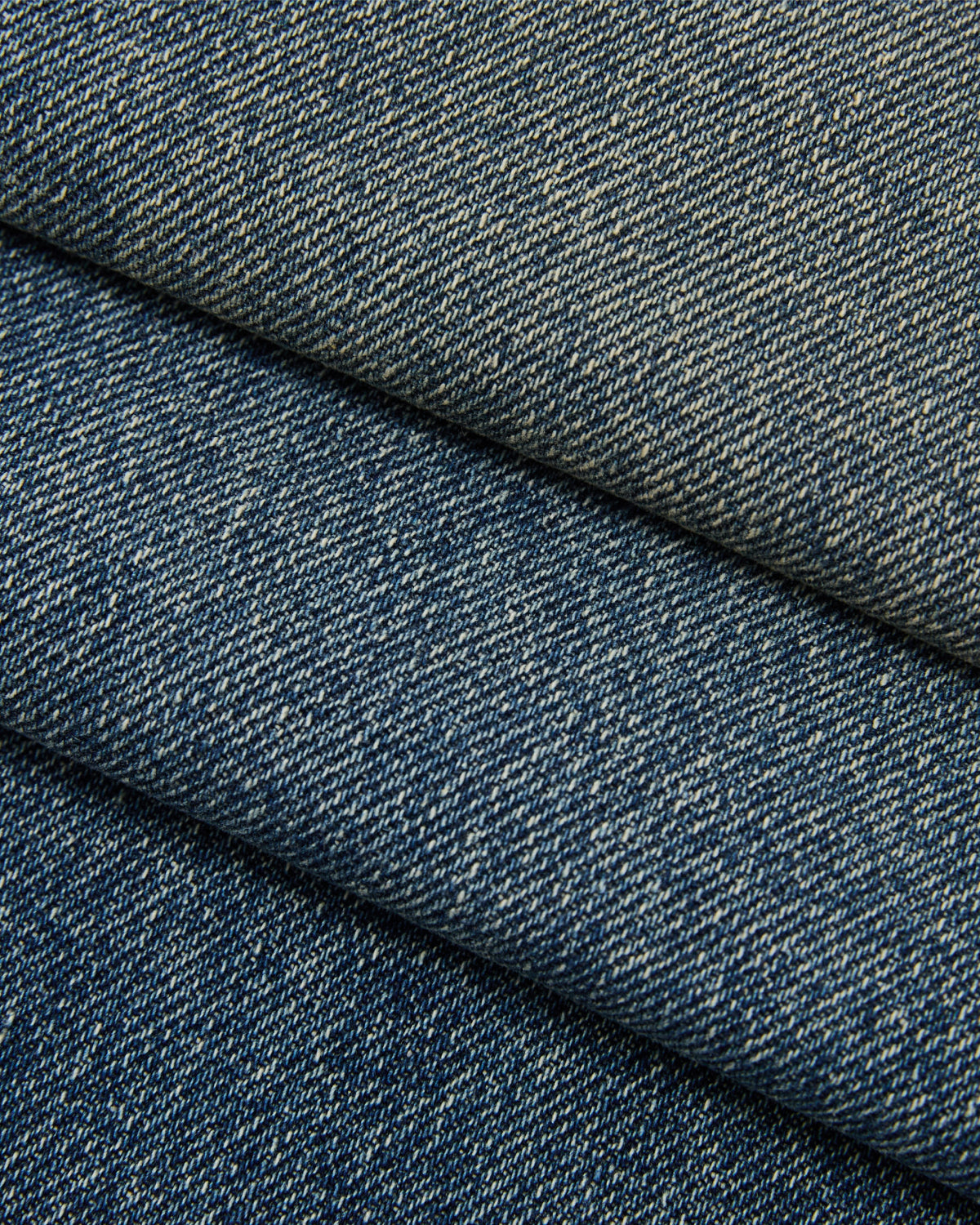 Close-up of folded Sundae School MEDIUM BLUE FRESHMAN FIT DENIM, showcasing the detailed texture and weave of the fabric.