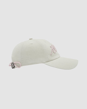 The Sundae School IVORY FLOWER KNOT CAP features light beige fabric, pink Hangul embroidery on the front, a curved brim, and a pink adjustable strap with black fastener, all set against a plain background for a vintage-core look.