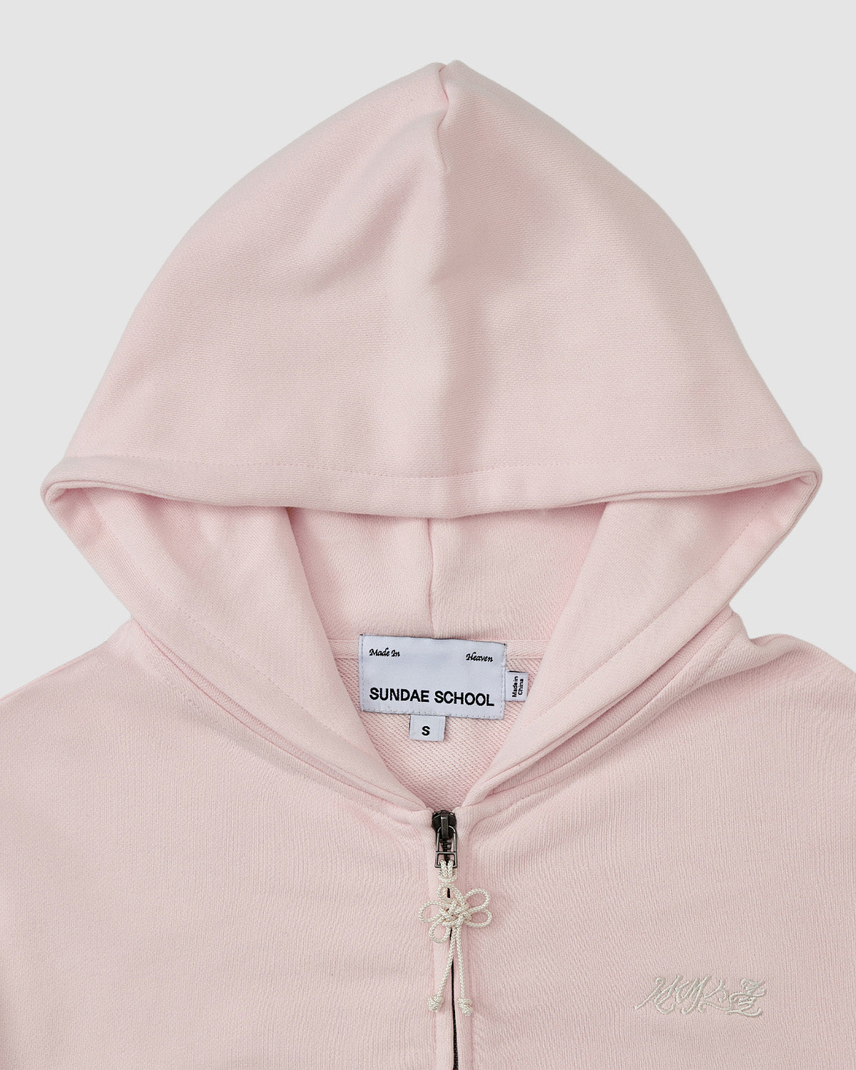The BABY PINK FLOWER KNOT ZIP UP HOODIE by Sundae School is a light pink unisex hoodie with a hood, front zipper, inside collar label, and Mugunghwa flower Korean embroidery plus text detail on the left chest.