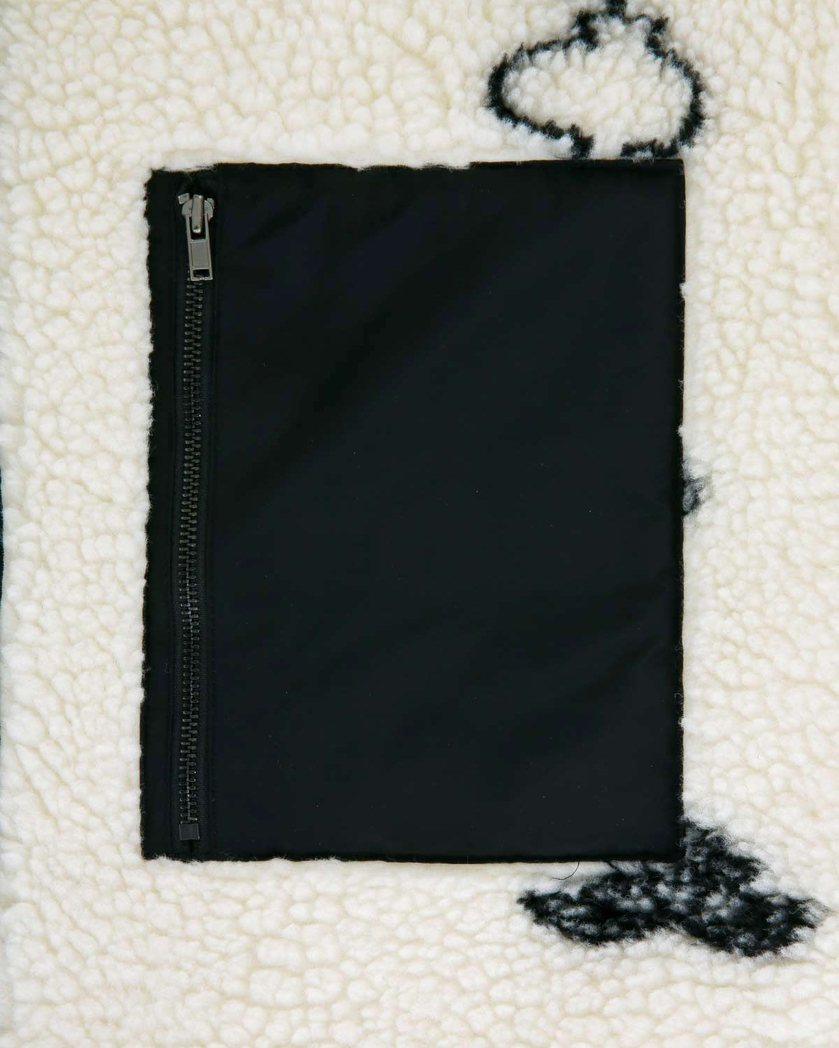 A close-up of the Kiwa Fleece Zip-Up by Sundae School shows a black zippered pocket on white jacquard fleece with black abstract patterns inspired by Korean calligraphy.