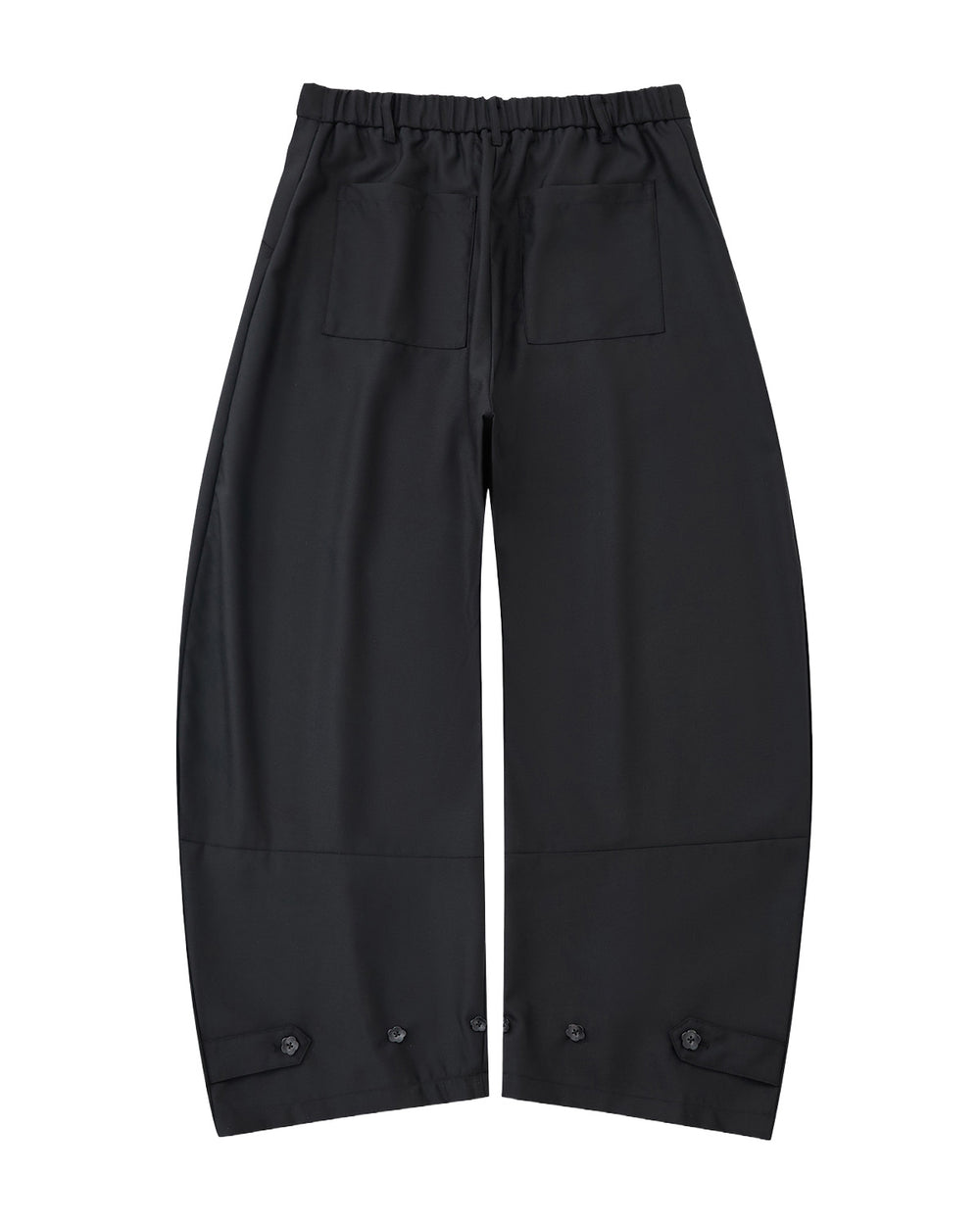 The BLACK PLEATED HANBOK SLACKS by Sundae School are loose-fitting black pants with an elastic waistband, two front patch pockets, and button details at the hems, shown on a light gray background.