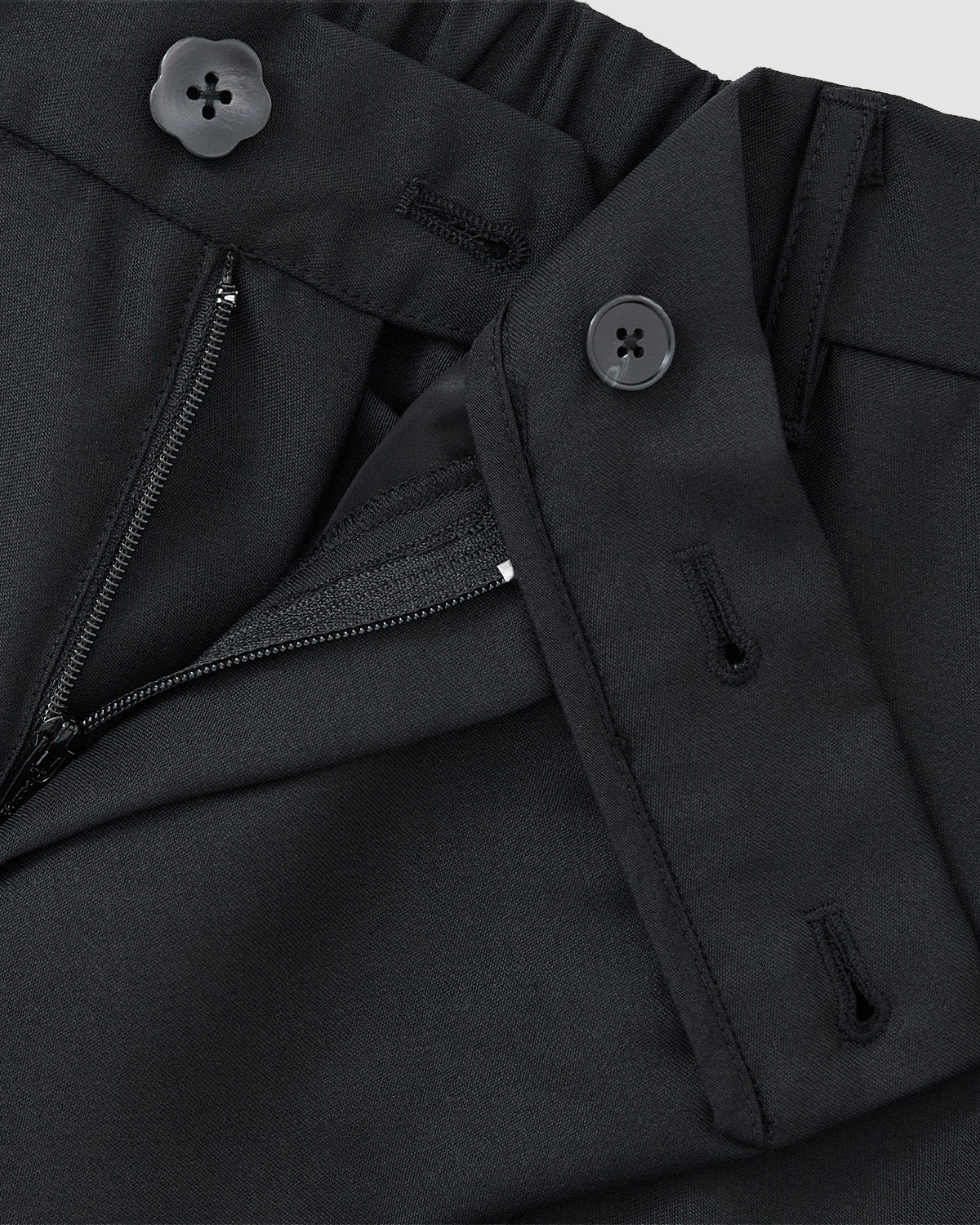 Close-up of Sundae School’s BLACK PLEATED HANBOK SLACKS, featuring an open zipper, two buttons, and detailed waistband, showcasing the rich fabric texture.