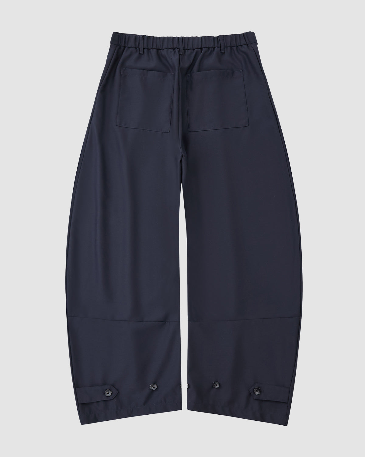 Sundae School NAVY PLEATED HANBOK SLACKS featuring an elastic waistband, two back pockets, and adjustable button cuffs, shown flat on a white background.