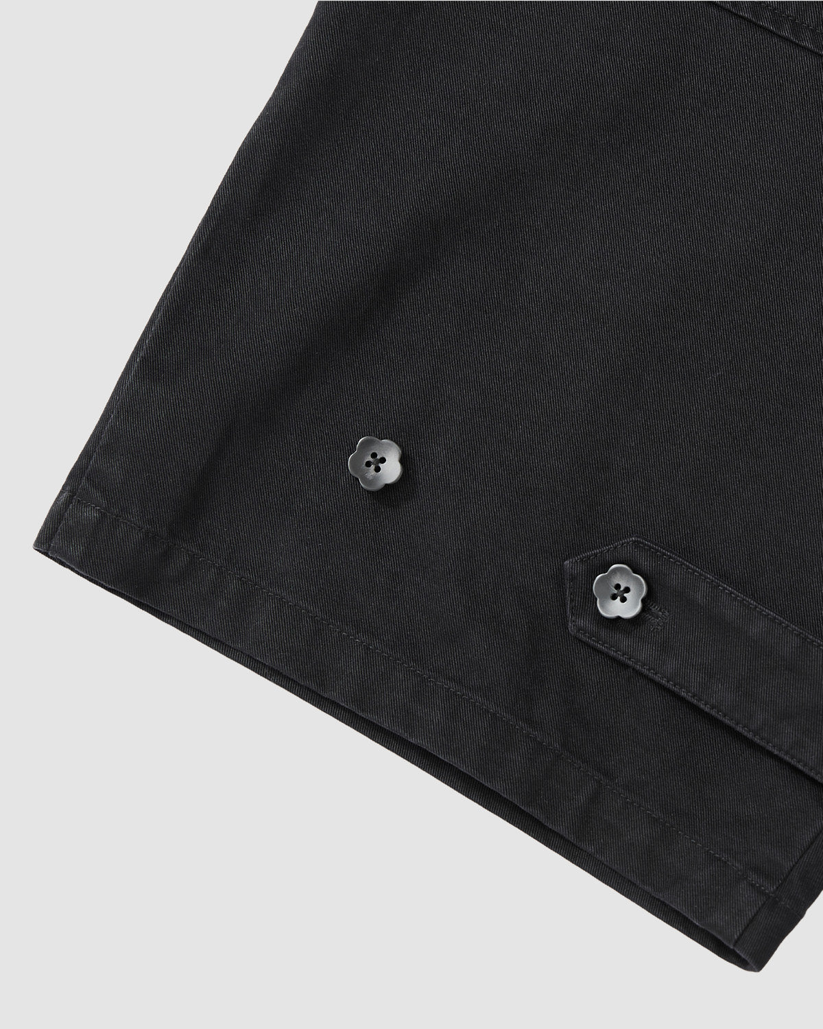 Close-up of the BLACK HANBOK CHINO PANTS by Sundae School, highlighting the sleeve's edge with visible seams and two black flower-shaped buttons—accents that enhance the hanbok-inspired silhouette.
