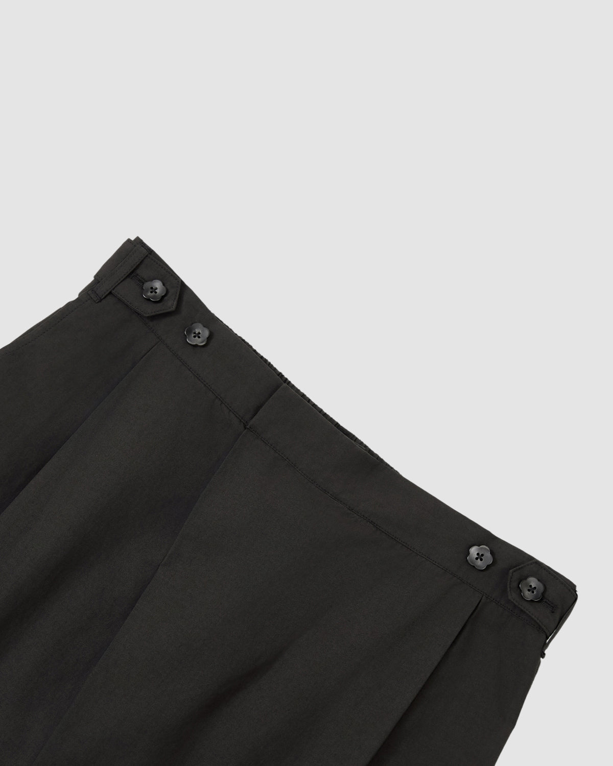 Close-up of the waist on Sundae School’s BLACK HANBOK LINEN PANTS, showing pleats and two black buttons per side near the waistband, set against a light gray background.
