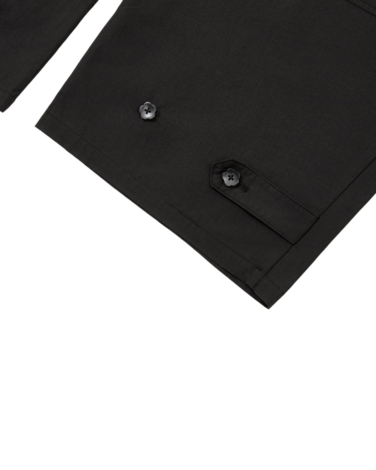 Close-up of a black garment, possibly a jacket sleeve, showcasing a pocket with a buttoned flap and another visible button on the fabric. Set against a plain white background, the image echoes the refined details found in Sundae School’s BLACK HANBOK LINEN PANTS, known for their adjustable waist and cotton-linen blend.