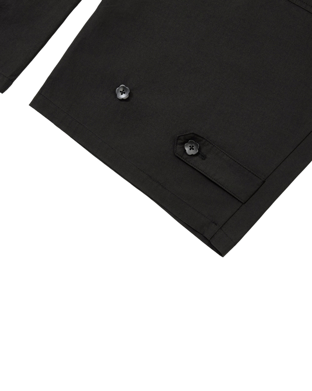 Close-up of a black garment, possibly a jacket sleeve, showcasing a pocket with a buttoned flap and another visible button on the fabric. Set against a plain white background, the image echoes the refined details found in Sundae School’s BLACK HANBOK LINEN PANTS, known for their adjustable waist and cotton-linen blend.