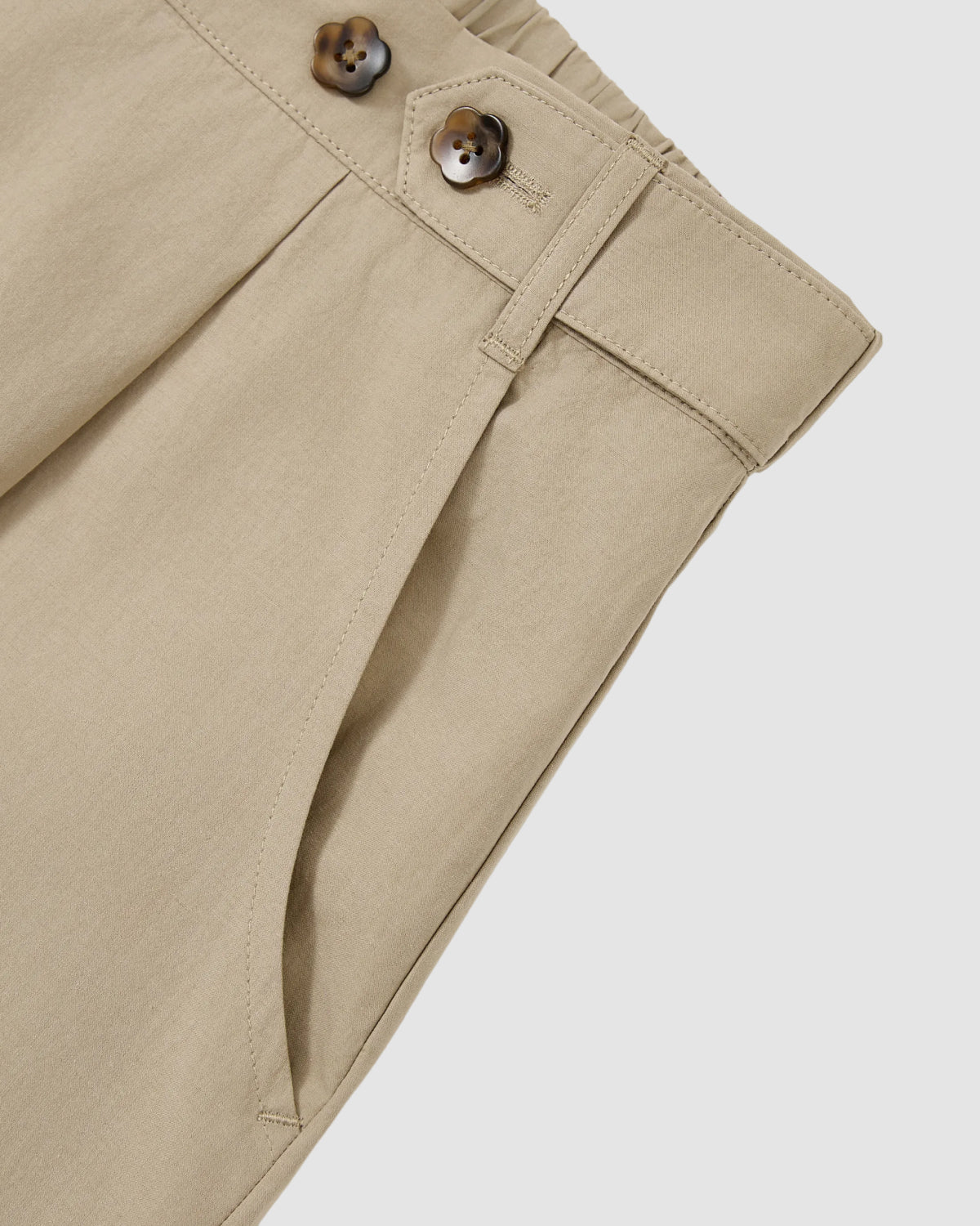 Close-up of Sundae School’s WHEAT HANBOK LINEN PANTS, showcasing beige cotton-linen fabric, pleated front, adjustable waist with two brown buttons, side pocket, set against a plain light background.