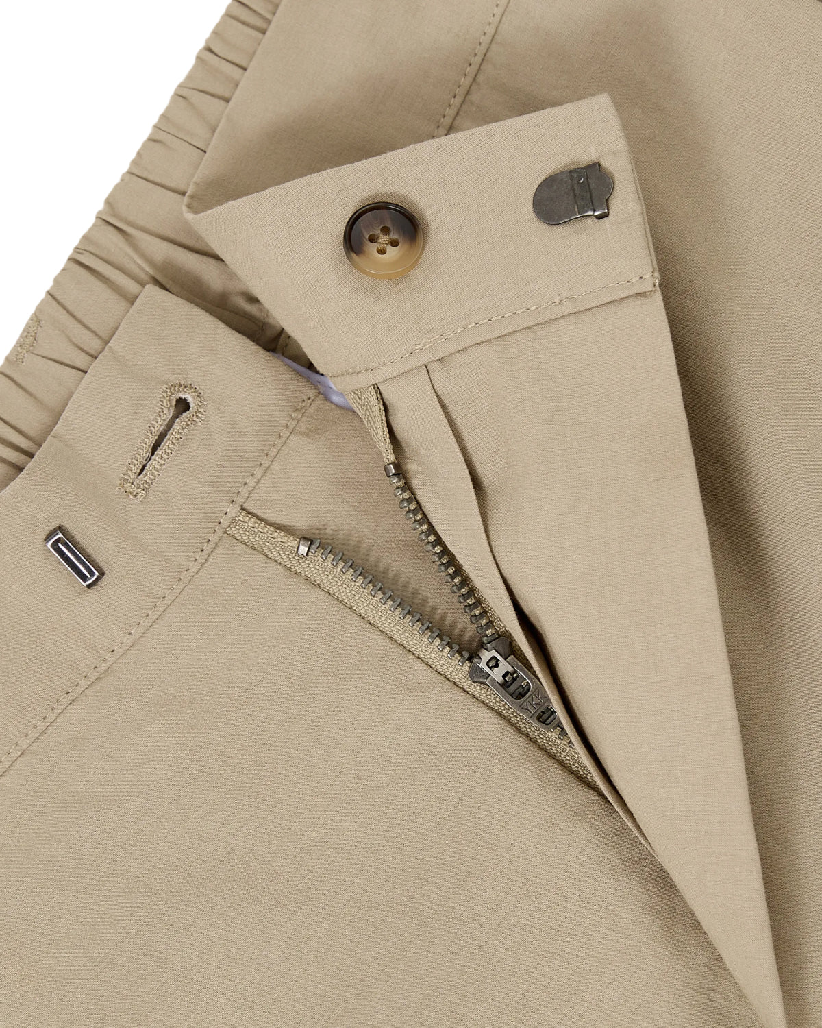 Close-up of WHEAT HANBOK LINEN PANTS by Sundae School, featuring a partially unzipped metal zipper, button, and metal hook closure at the waistband. The tan fabric resembles cotton or linen, emphasizing the comfortable fit characteristic of these balloon-style pants.