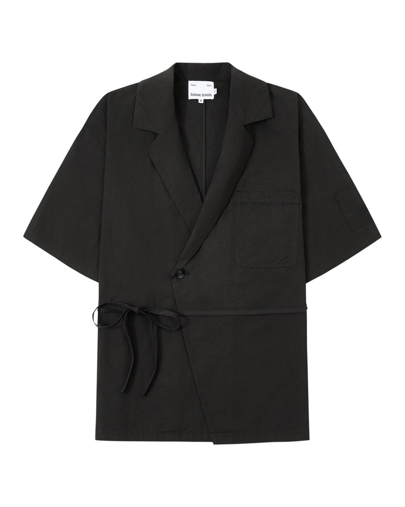 The BLACK HANBOK LINEN SHIRT by Sundae School is a black, short-sleeve blazer-style jacket inspired by the cotton linen hanbok, featuring a chest pocket, side tie closure, single button, and notched lapels, laid flat on a white background.