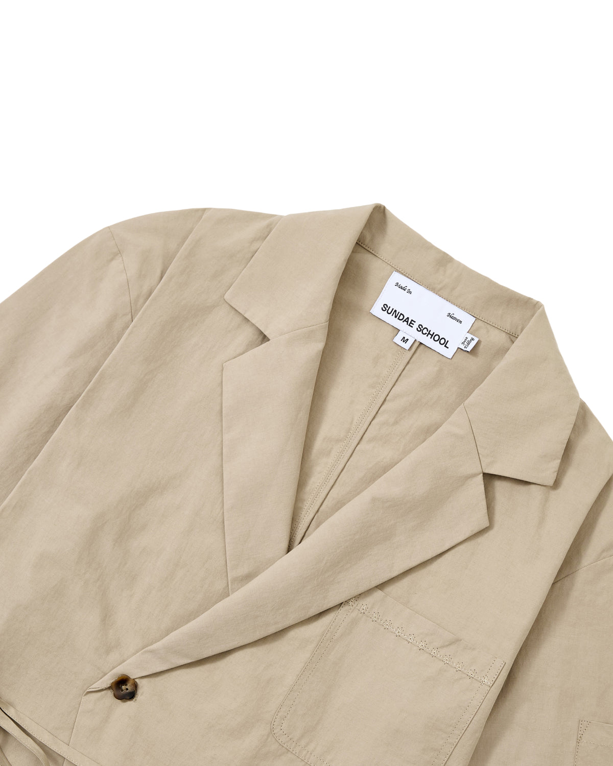 Cropped image of a beige blazer with a chest pocket and a single button, featuring a visible Sundae School label, styled over the WHEAT HANBOK LINEN SHIRT—a lightweight cotton linen blend summer shirt from Sundae School.