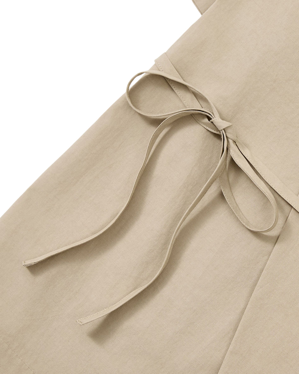 Close-up of the WHEAT HANBOK LINEN SHIRT by Sundae School, crafted from a soft cotton-linen blend in beige, featuring a fabric belt tied in a bow at the waist and showcasing its smooth texture and clean stitching.