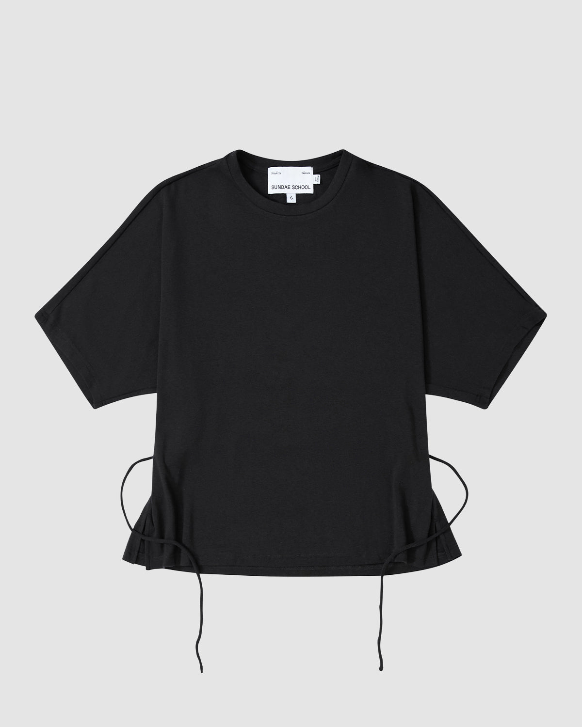 The BLACK BAERAE T-SHIRT by Sundae School is a plain black short-sleeved tee with a round neckline and adjustable drawstrings at the hem, inspired by the Korean durumagi overcoat, shown on a flat light gray background.