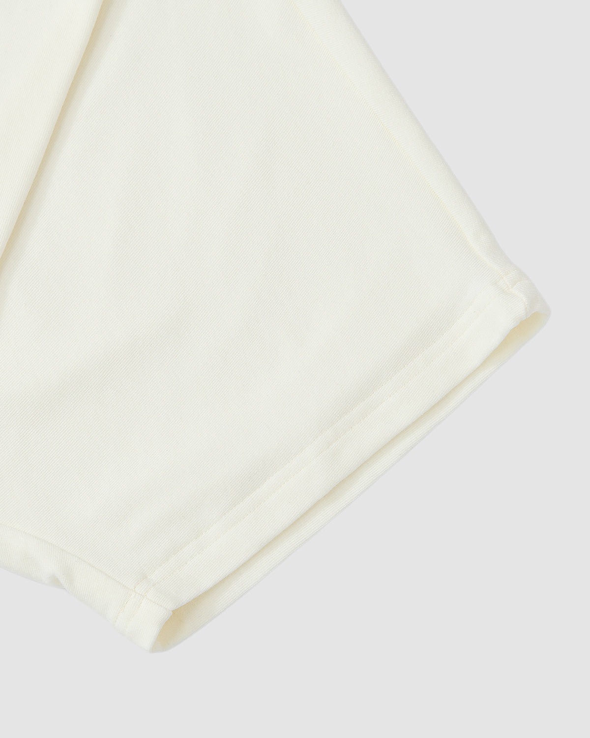 Close-up of the sleeve and side seam of the Sundae School IVORY BAERAE T-SHIRT, inspired by the traditional Korean overcoat durumagi. The soft, subtly textured fabric is shown against a light gray background.