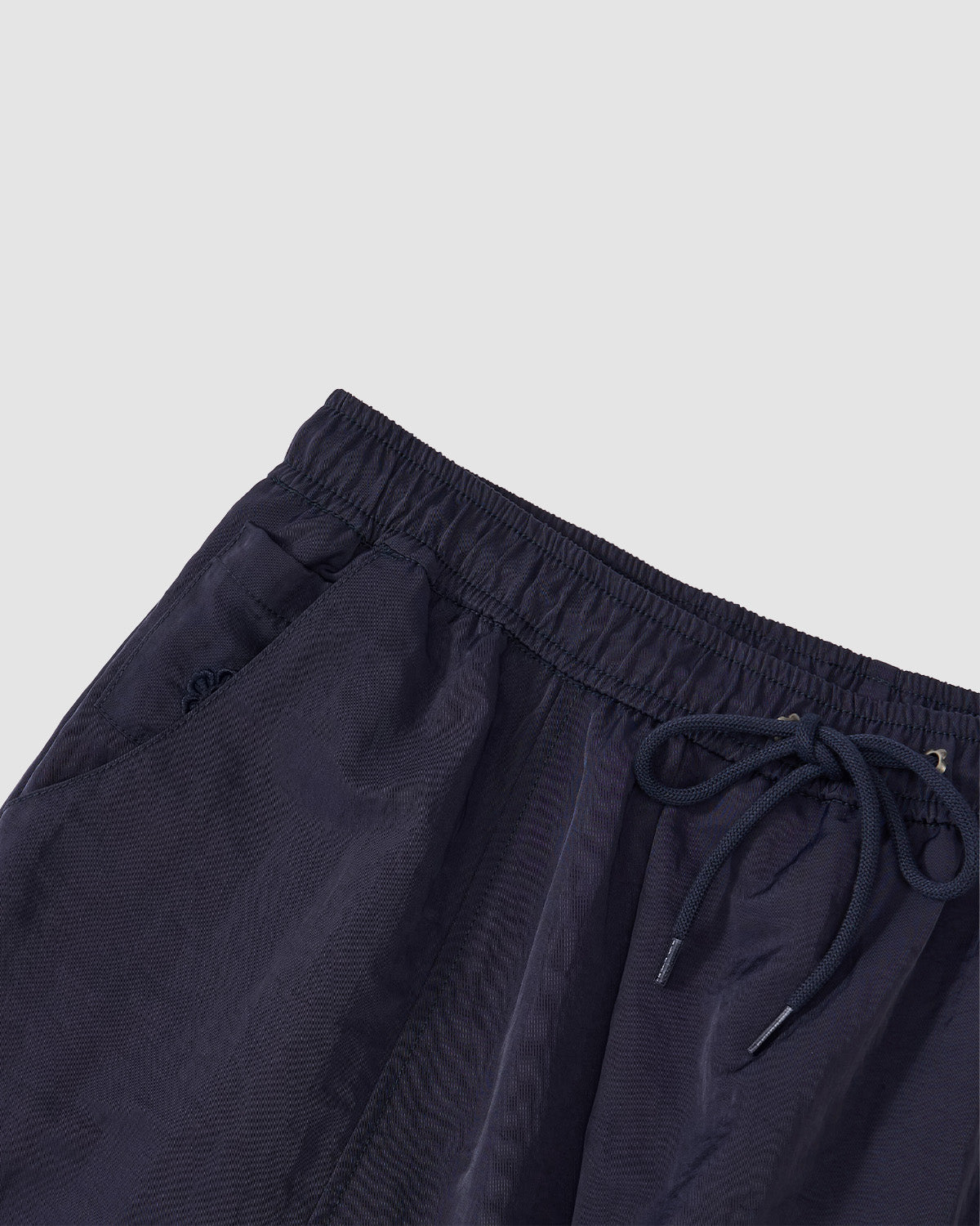 Close-up of Sundae School’s NAVY HANBOK BALLOON TRACK PANTS with an elastic waistband, metal-tipped drawstrings, side pockets, and adjustable hems, displayed flat on a light gray background.