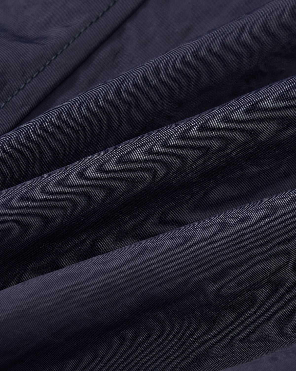 Close-up of Sundae School’s NAVY HANBOK BALLOON TRACK PANTS, showing dark, textured fabric with diagonal lines and folds that create depth and softness—evoking the unique curved barrel silhouette of these adjustable-hem pants.