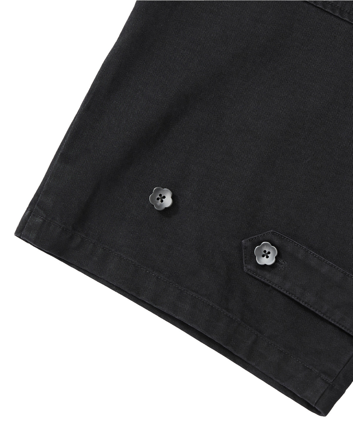 Close-up of the BLACK HANBOK CHINO PANTS by Sundae School, showcasing washed black cotton chino fabric with two black flower-shaped buttons and a partially visible stitched flap near the hem.