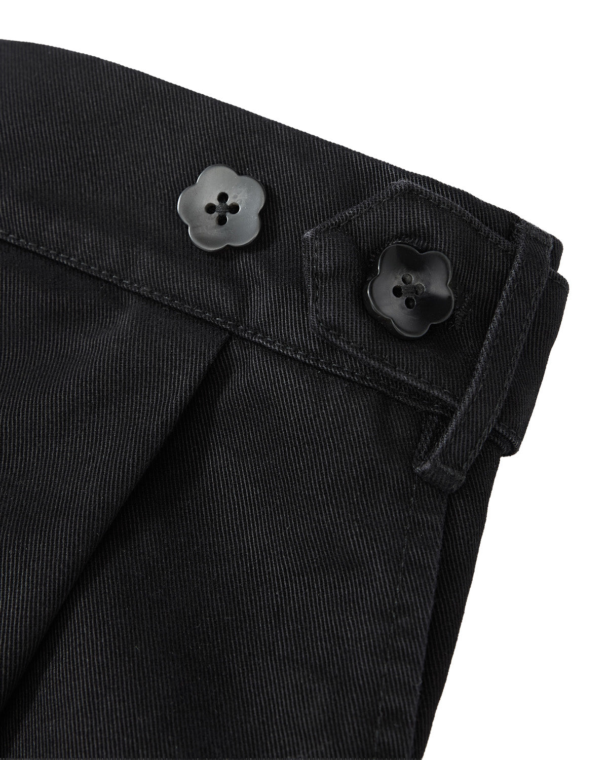 Close-up of Sundae School’s BLACK HANBOK CHINO PANTS, showcasing black fabric with two flower-shaped black buttons, a tailored waistband, and a relaxed barrel-fit silhouette inspired by traditional hanbok pants.