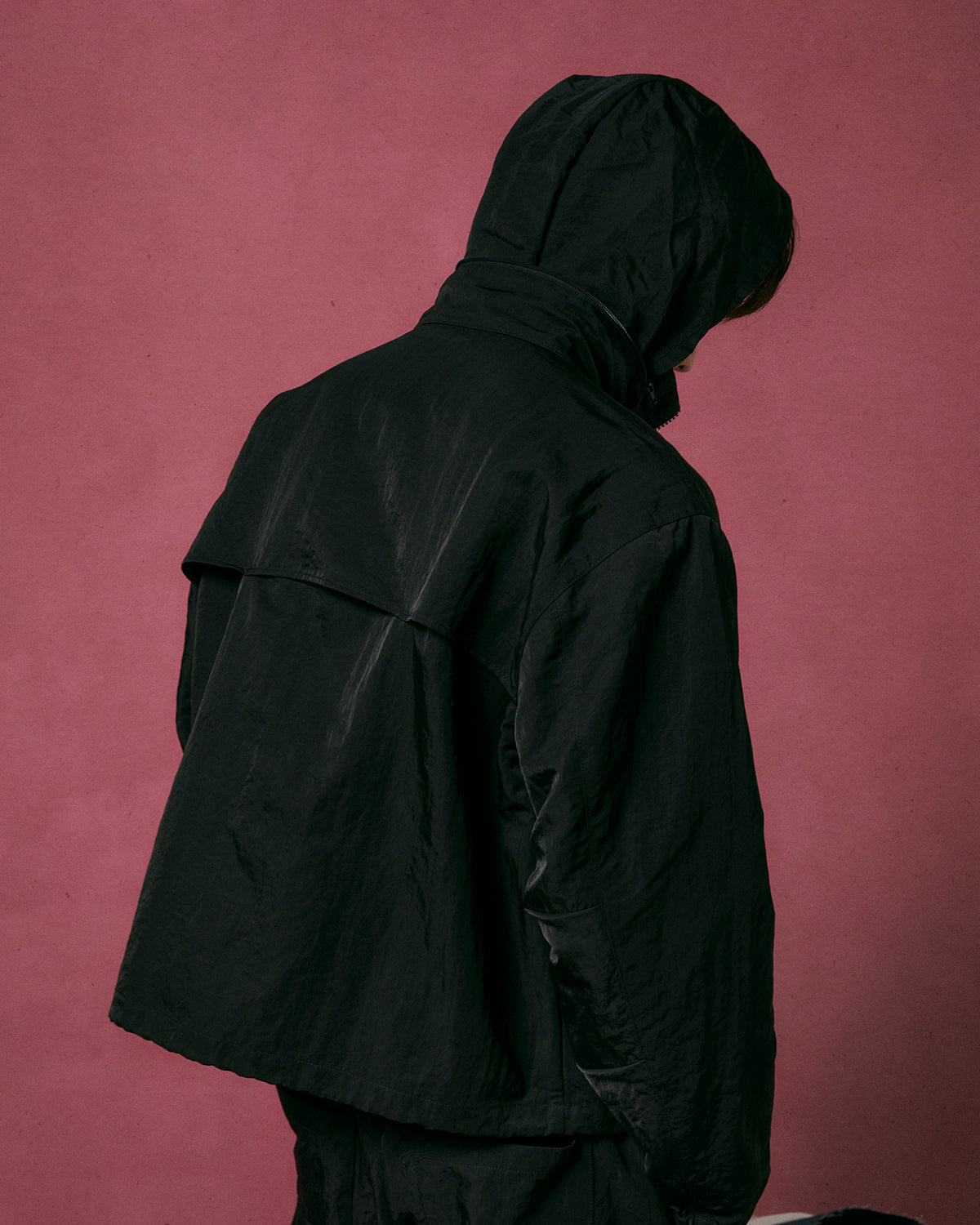 A person models the Sundae School BLACK HANBOK TRACK JACKET, standing with their back to the camera against a muted pink background.