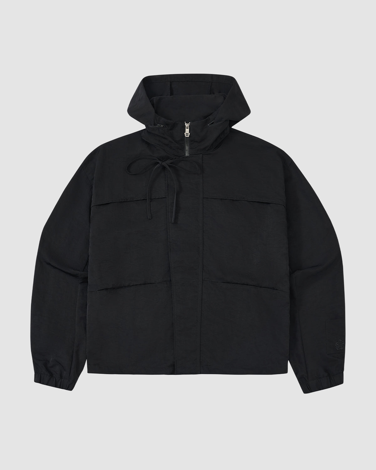 The BLACK HANBOK TRACK JACKET by Sundae School features long sleeves, a front zipper, two large pockets, and adjustable hood drawstrings. Crafted from lightweight nylon in black, it's shown against a plain light gray background.
