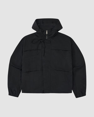 The BLACK HANBOK TRACK JACKET by Sundae School features long sleeves, a front zipper, two large pockets, and adjustable hood drawstrings. Crafted from lightweight nylon in black, it's shown against a plain light gray background.