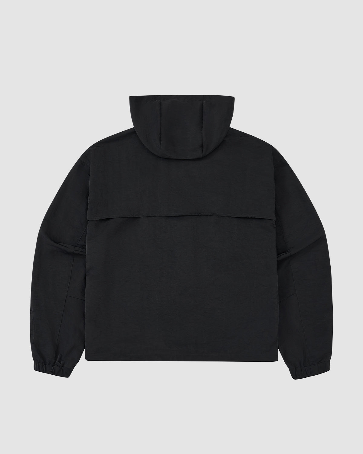The BLACK HANBOK TRACK JACKET by Sundae School is a lightweight nylon, hooded jacket with long sleeves, elastic cuffs, and a horizontal flap on the upper back. Shown from the back against a light gray background.