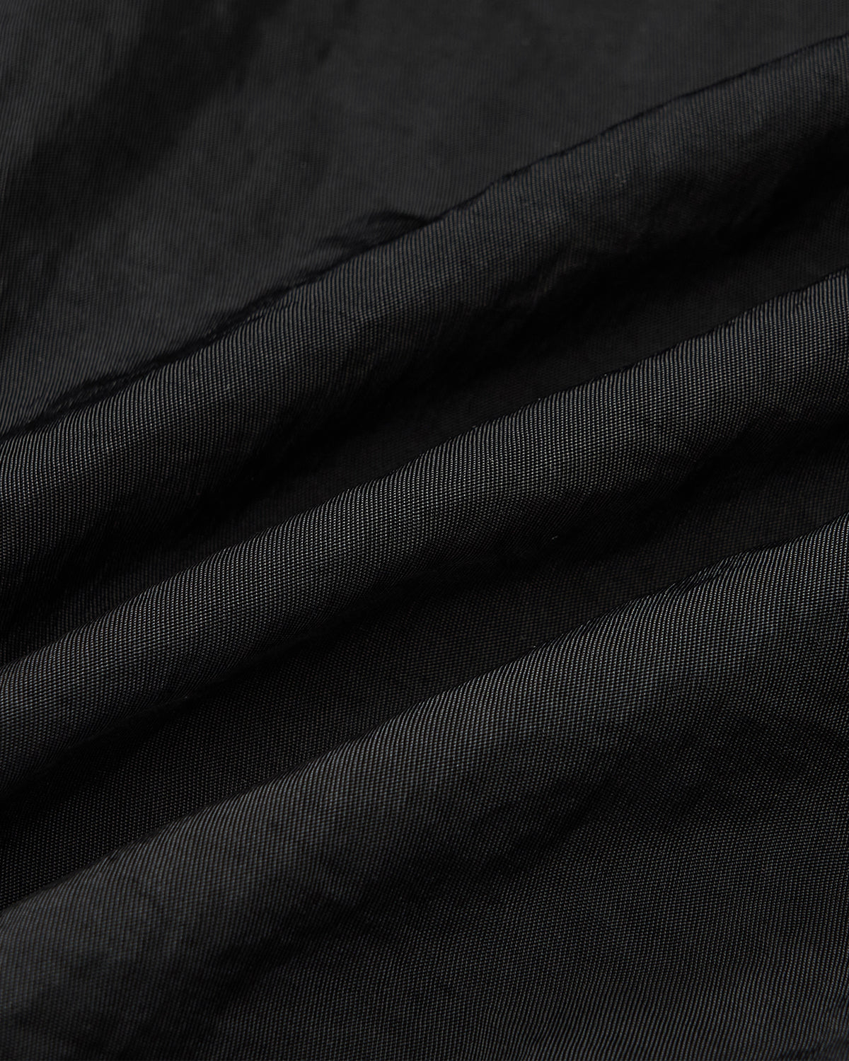 A close-up of Sundae School’s BLACK HANBOK TRACK JACKET highlights its fine, diagonal ribbing and soft folds, showcasing the textured fabric and subtle sheen.