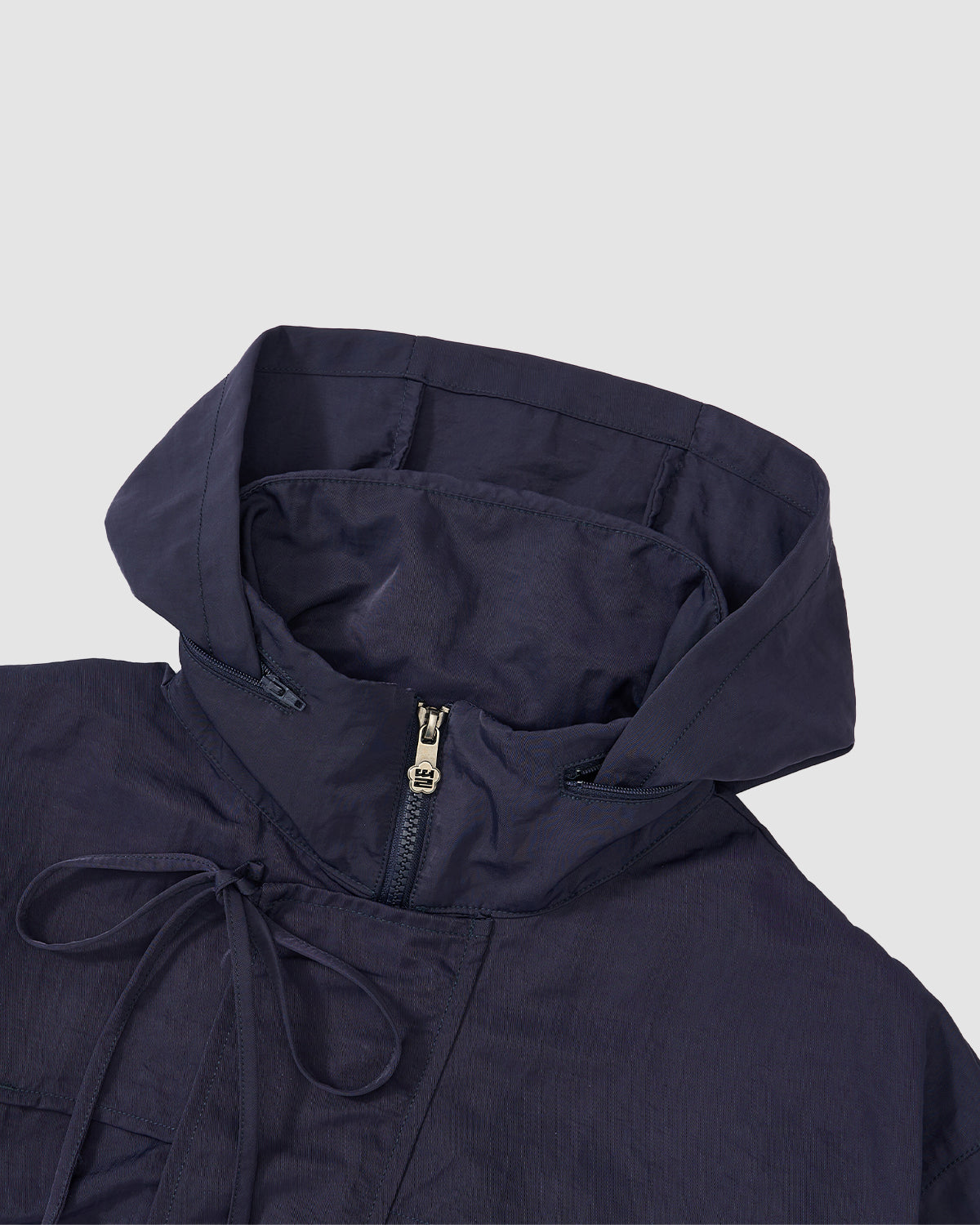 A close-up of the Sundae School NAVY HANBOK TRACK JACKET, made from lightweight nylon with a partial front zipper, custom 떨 zipper pull, and neckline drawstring, shown on a light gray background.