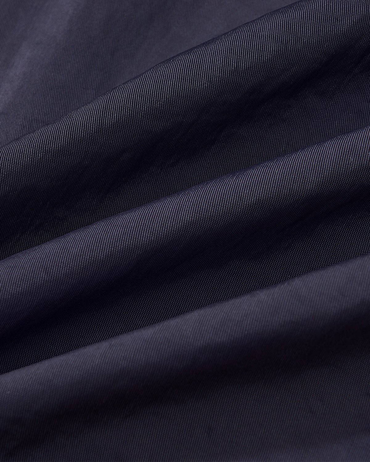 Close-up of Sundae School’s NAVY HANBOK TRACK JACKET, showing the dark navy fabric with diagonal weave, soft pleats, and a peek at the custom 떨 zipper pull.