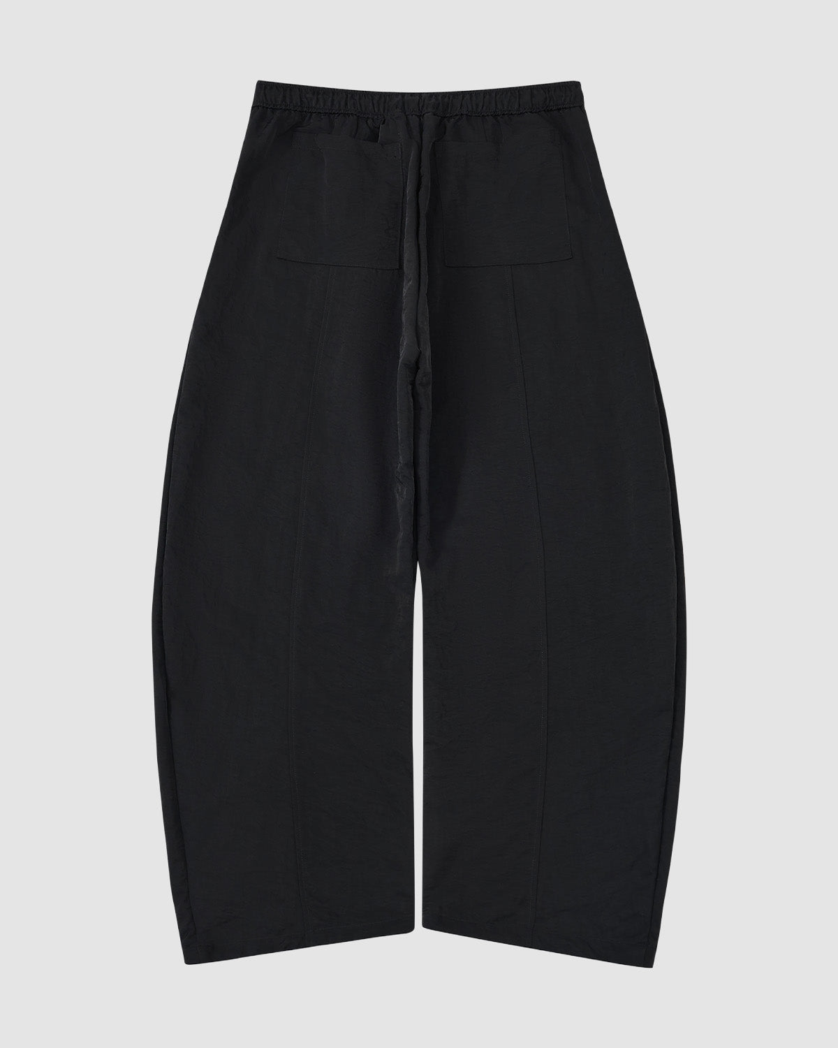The BLACK HANBOK BALLOON TRACK PANTS by Sundae School are loose-fitting black nylon track pants with an elastic waistband, front patch pockets, and wide, slightly tapered legs in a curved barrel silhouette, shown flat on a light gray background.