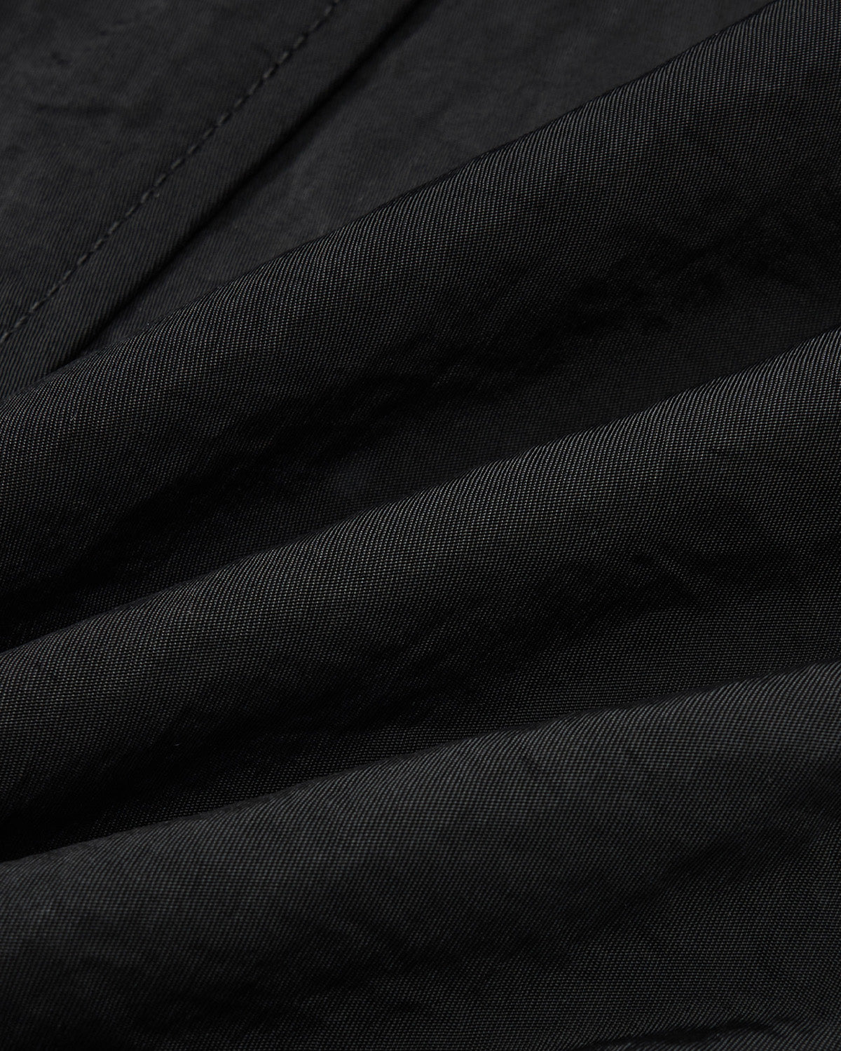 Close-up of Sundae School’s BLACK HANBOK BALLOON TRACK PANTS fabric, showing the fine weave, visible stitching, and diagonal creases that highlight the windproof, water-resistant technical nylon’s premium quality and detailed craftsmanship.