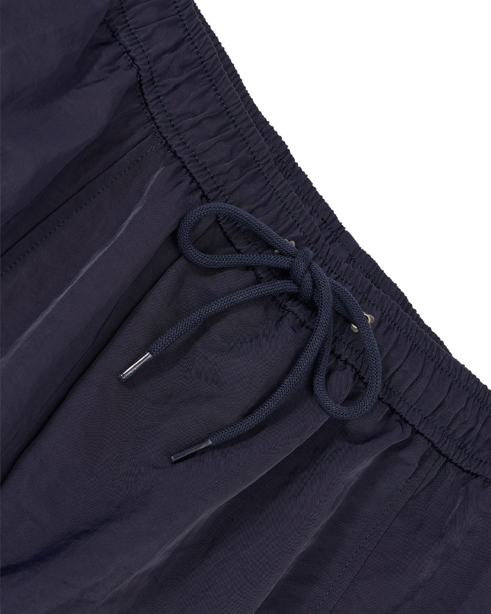 Close-up of dark navy athletic pants showing the elastic waistband, drawstring, and textured fabric against a white background.