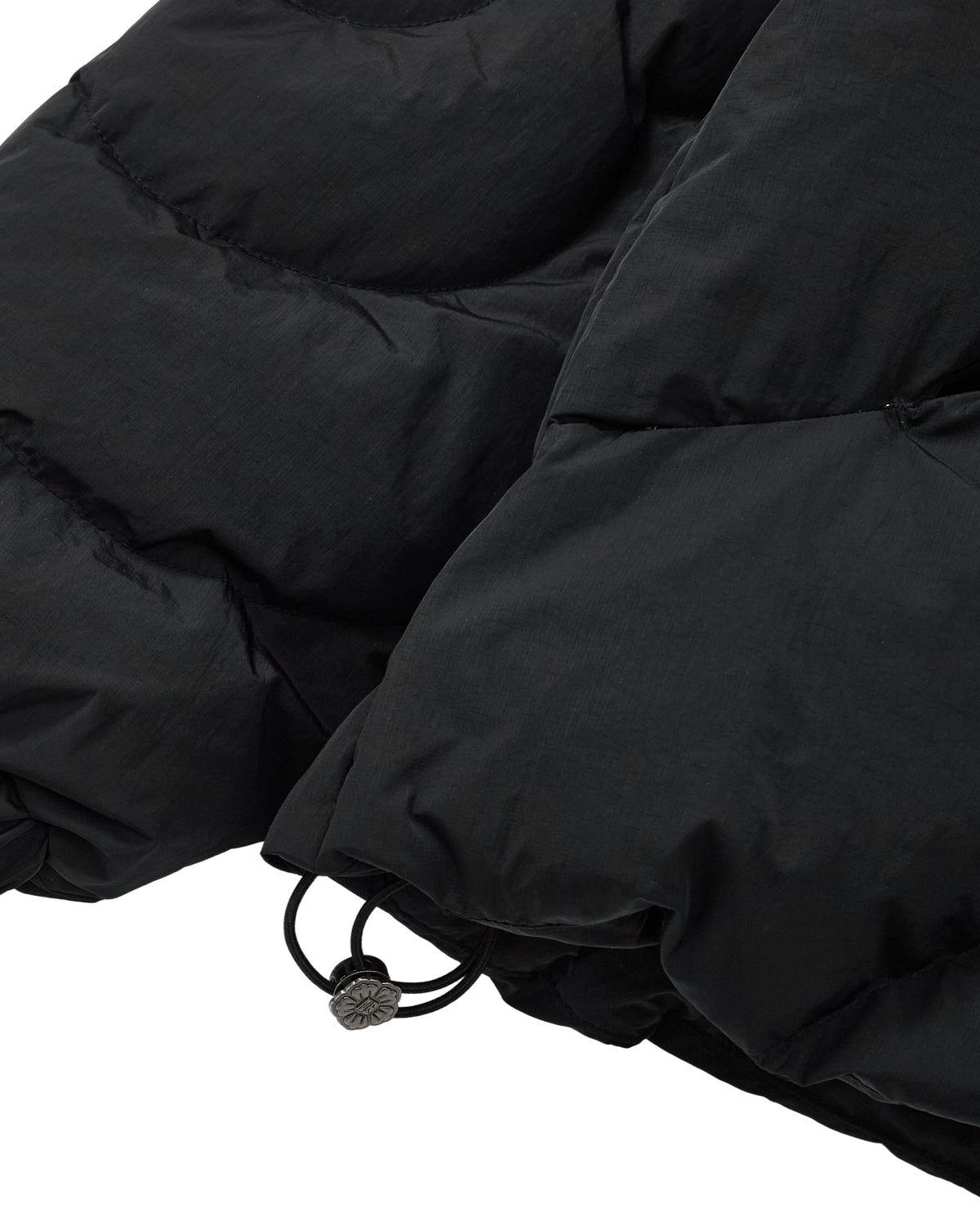 Close-up of the lower section of the BLACK HEAVYWEIGHT MOCHI PUFFER by Sundae School, highlighting an elastic drawstring and adjustable toggle at the hem. Inspired by the structure of a Korean hanbok jacket, this heavyweight puffer features premium duck down fill for exceptional warmth.