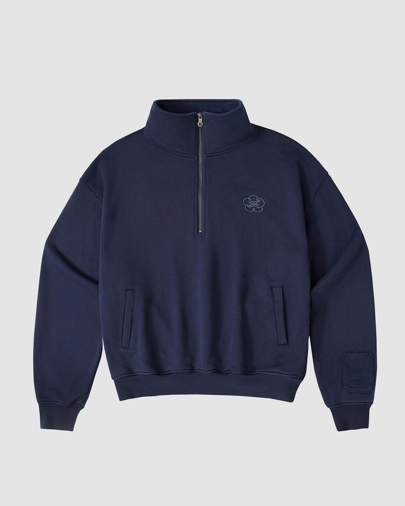 The Sundae School NAVY HESTER QUARTER ZIP is an oversized navy pullover with a high collar, quarter zip, two side pockets (one stash pocket), ribbed cuffs and hem, and a subtle embroidered logo on the left chest, shown on a light background.