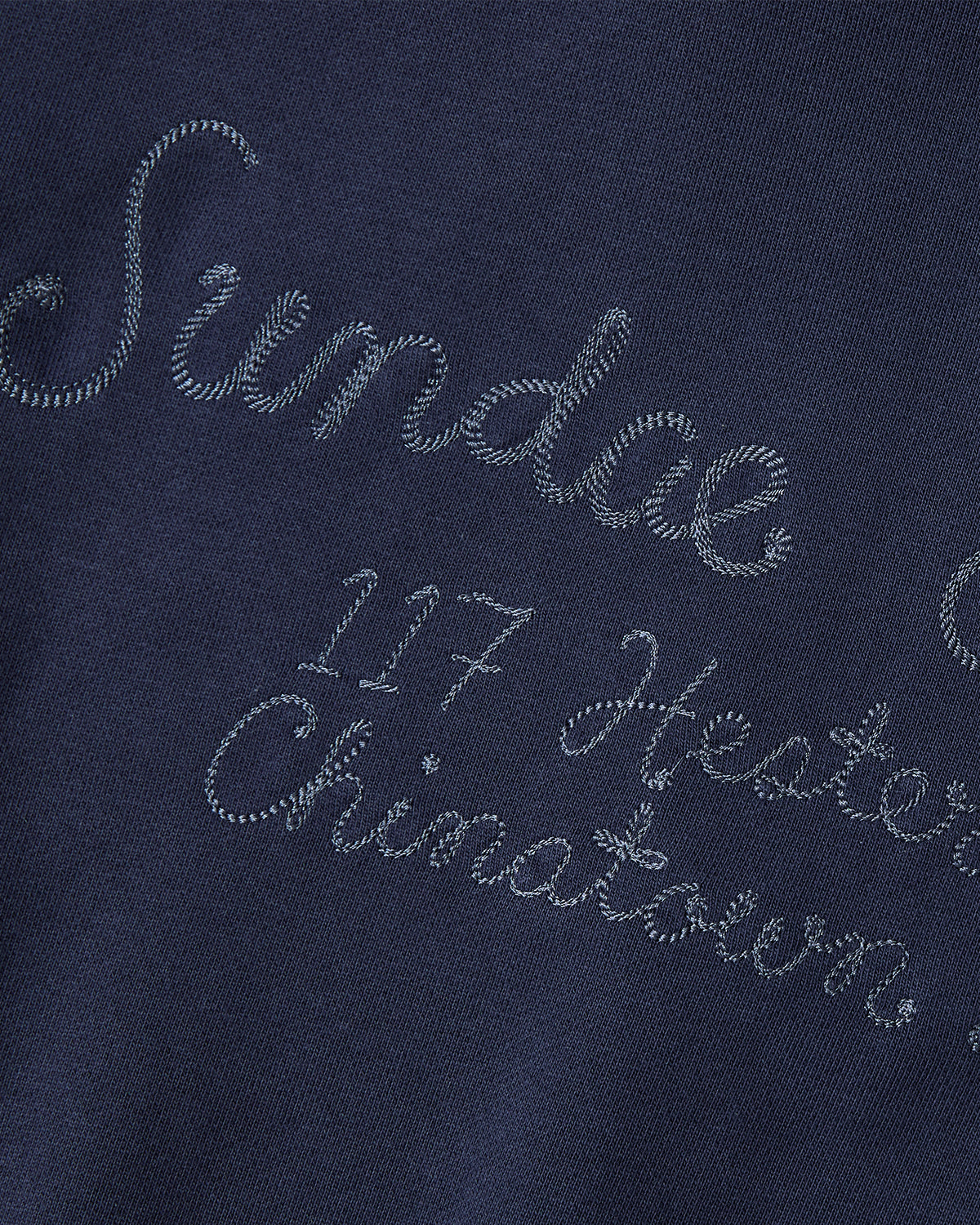 The NAVY HESTER QUARTER ZIP by Sundae School is a vintage cotton pullover featuring navy fabric and light blue embroidered cursive text that reads 